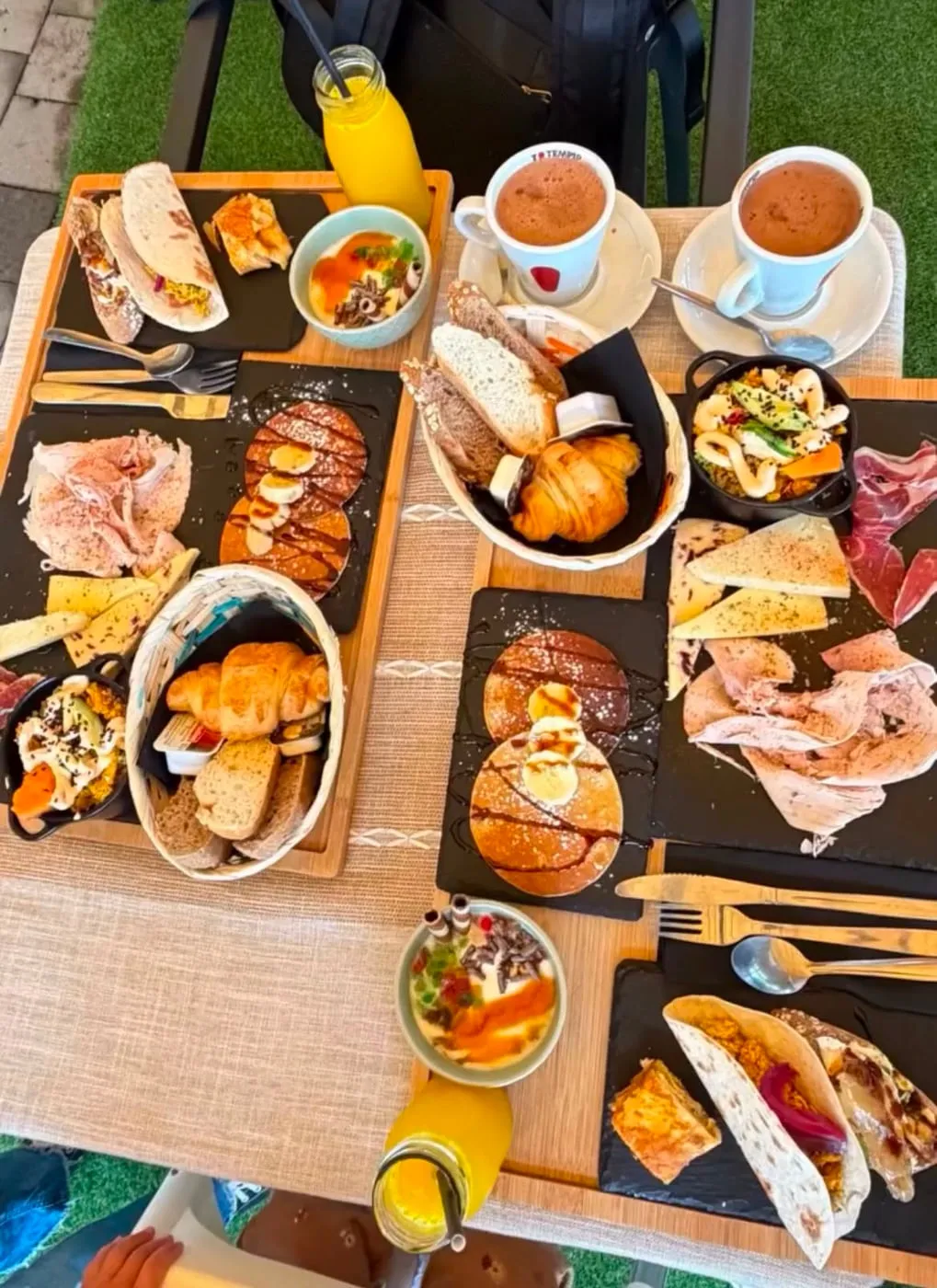 Brunch table for two, with pancakes, juices, breads, croissants and a quinoa bowl
