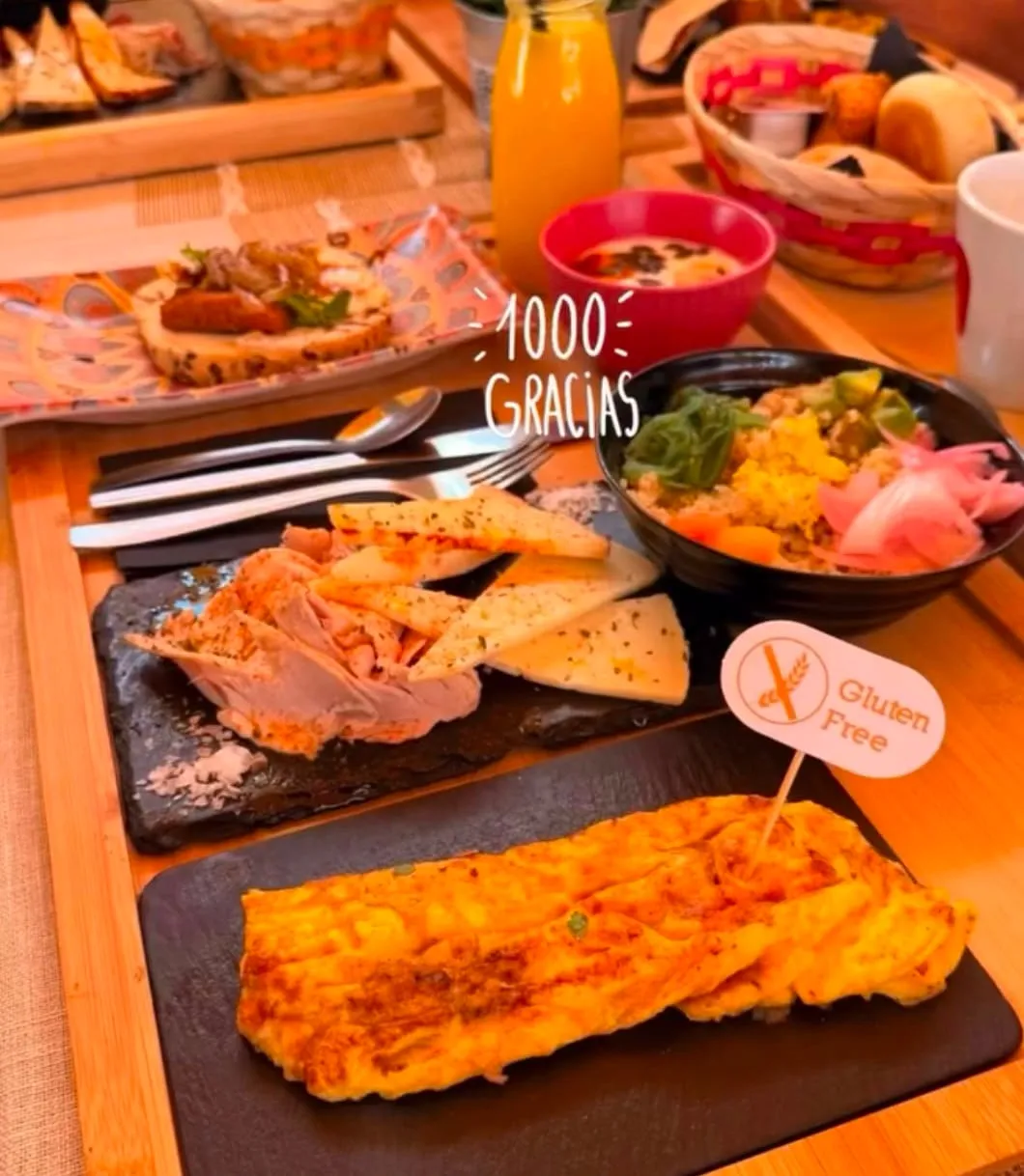 Gluten-free brunch: a cold cuts and cheese board, a quinoa bowl and an omelette, with its gluten-free flag