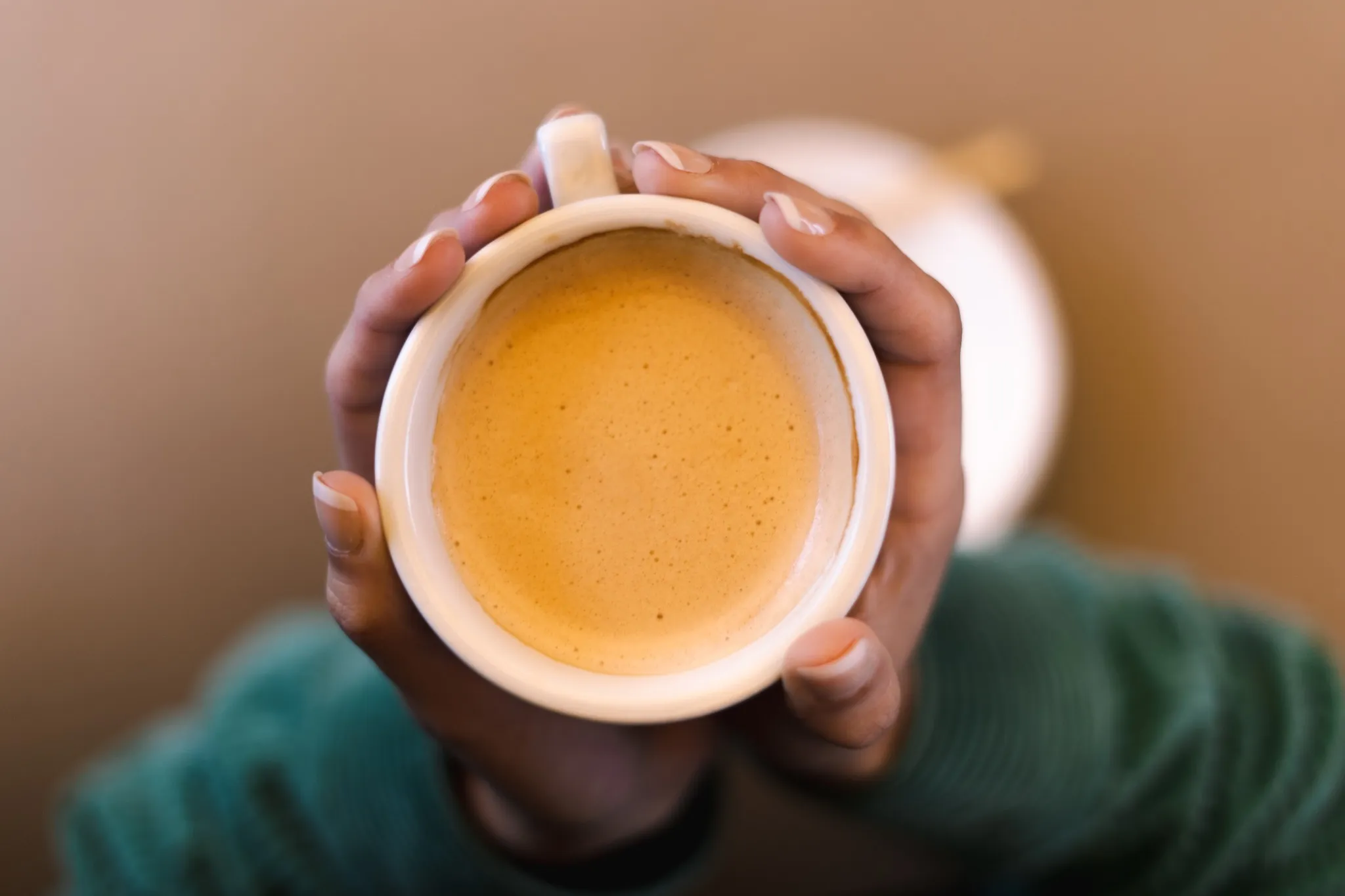 White coffee in a cup with the El Café de Manuela logo