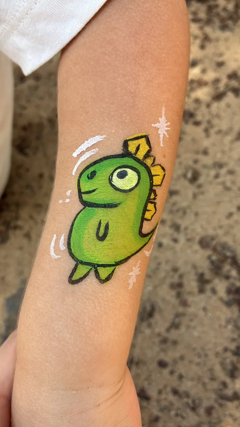 Un dinosaurio verde pintado en el brazo de un niño